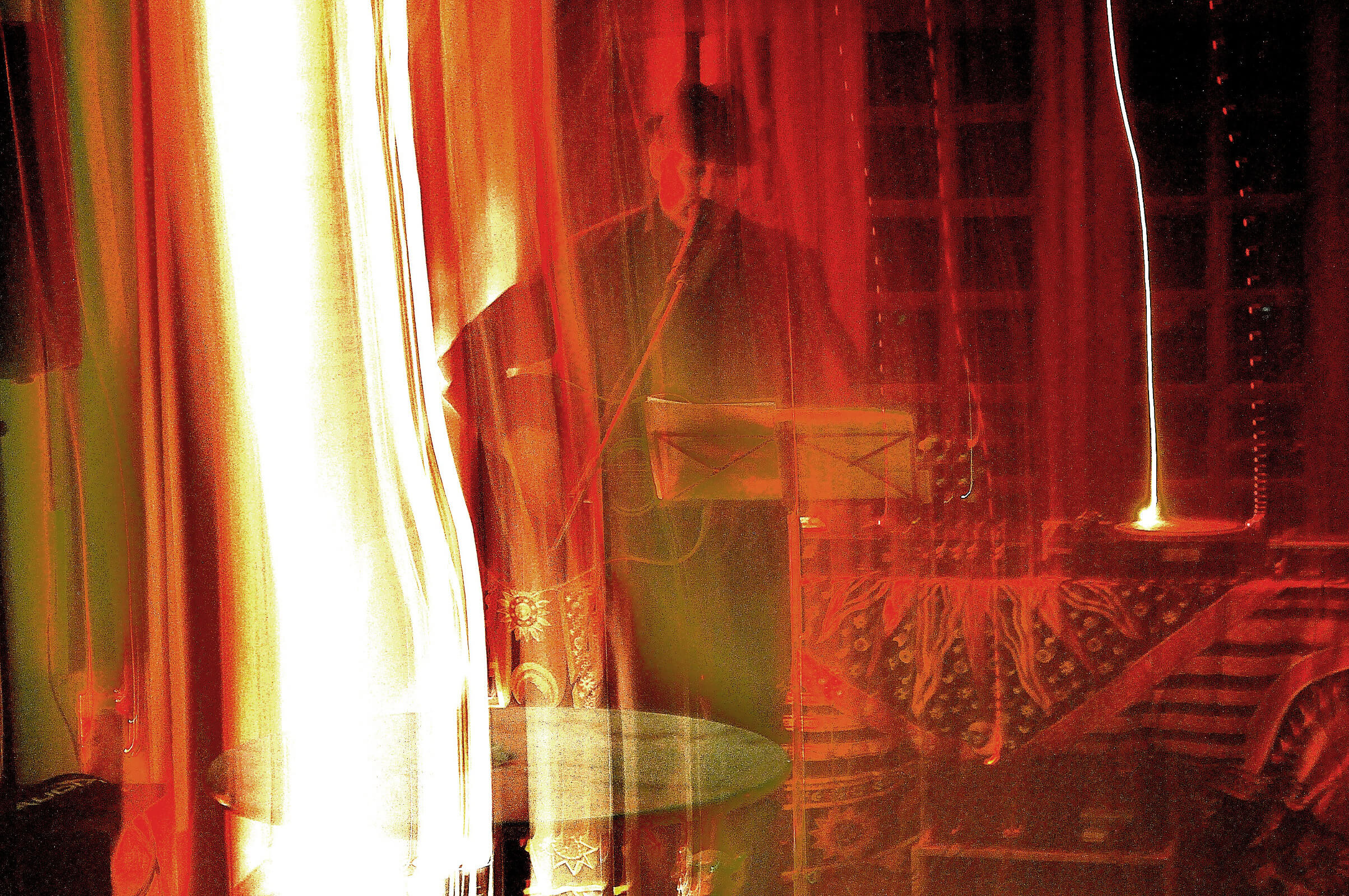 Langzeitbelichtungsartiges Bild meines Freundes Harald beim Auftritt mit Mikrofon- und Notenständer, verschleiert von senkrechten roten und gelben Lichtspuren.