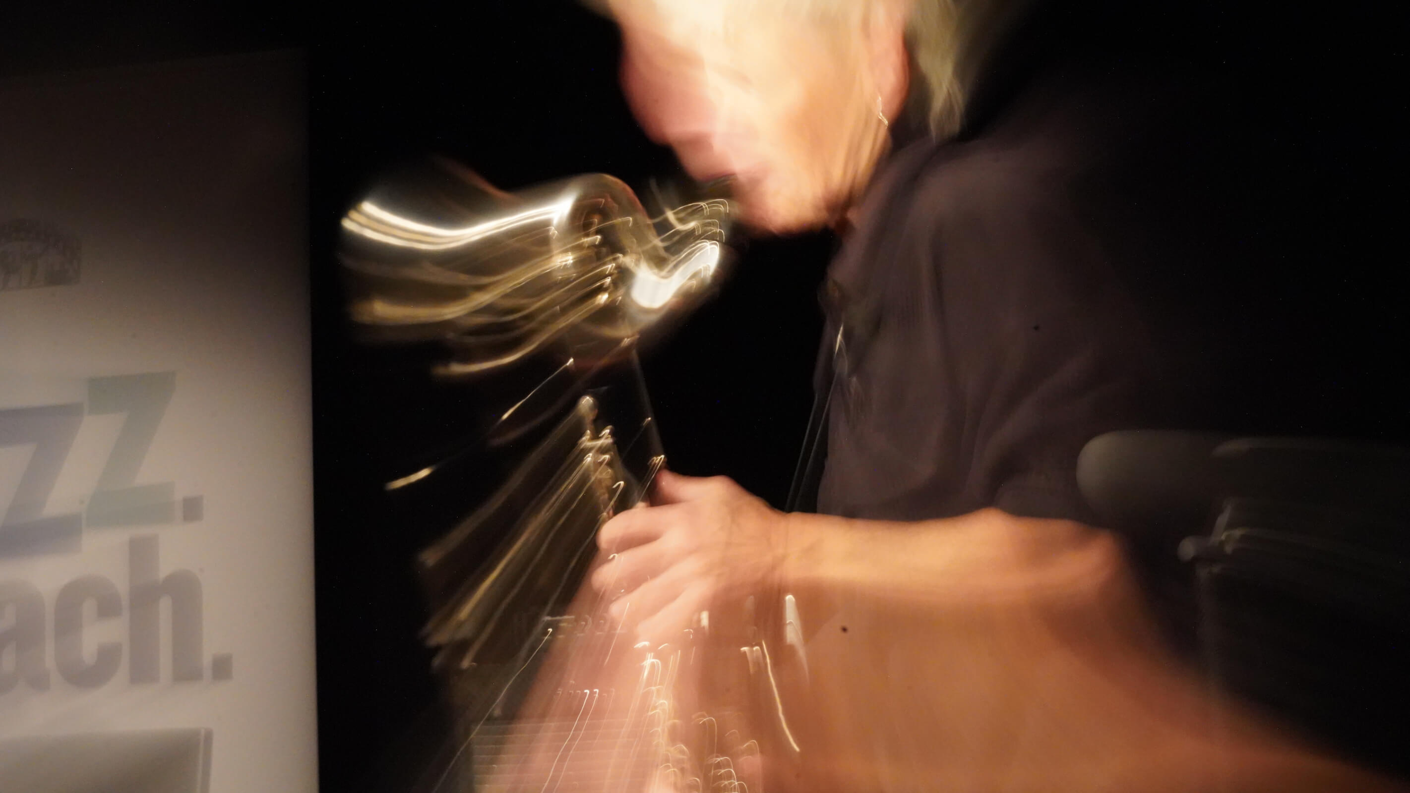 Bewegungsunschärfe einer Klarinettistin auf der Bühne, Instrument und Hände verwischt.